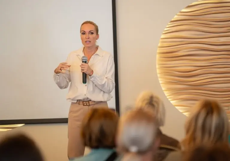 Előadó nő mikrofonnal beszél a közönségnek