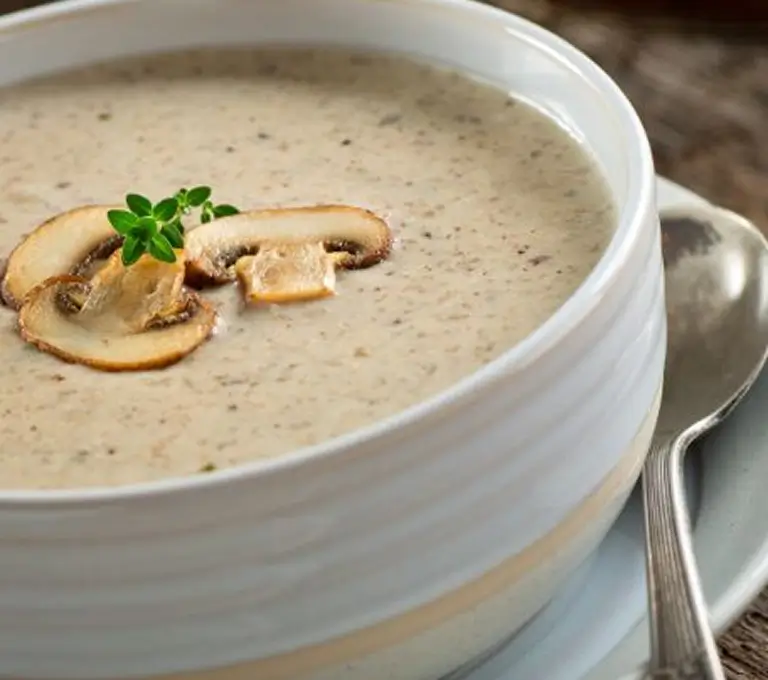 Gombakrémleves szeletelt gombával fehér tálban